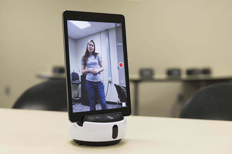 an ipad is docked in a piece of equipment and a student is on the ipad's screen which is in recording mode
