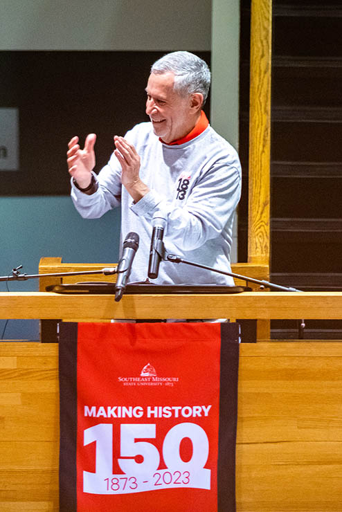 the university president Dr Carlos Vargas standing at a podium on a landing overlooking the floor below and clapping