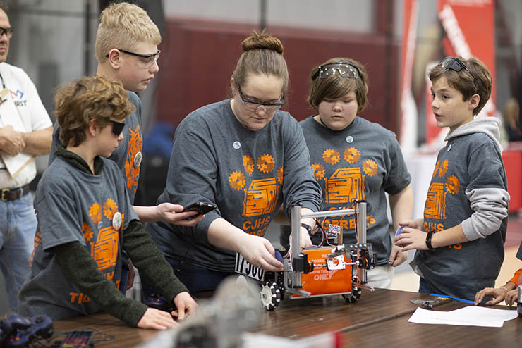a group of elementary school students and their teacher stand around a table working on a piece of roboti equipment