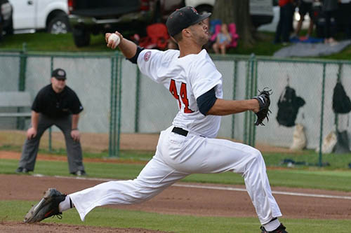 joey lucchesi on the pitchers mound halfway through deliverying a pitch to a batter