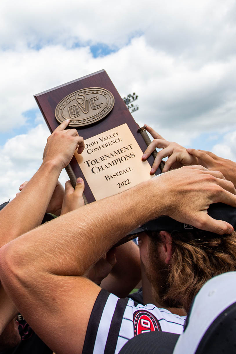 southeast's baseball team huddles together to celebrate and hold their trophy up