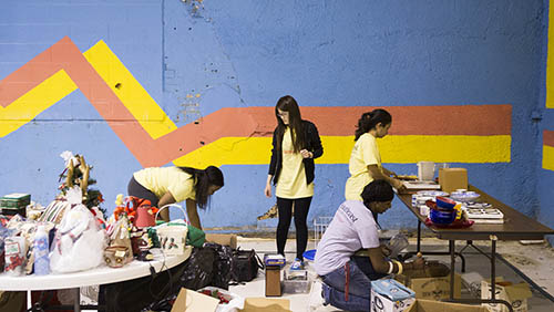 a group of students work in a room with blue walls and a yellow and faded red paint stripe on the wall