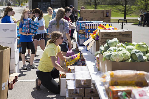 students outdoors working among boxes and boxes of food and vegetables