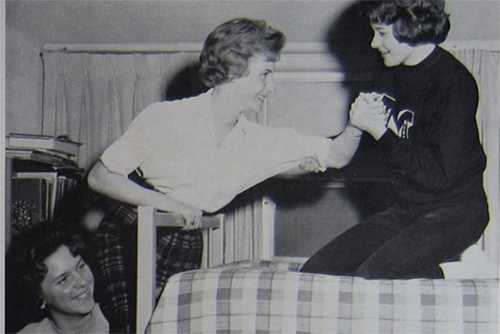 three young women around the 50s-60s climbing into a bunk bed in their dorm room