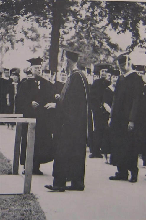 graduates from a previous decade of Southeast in their commencement regalia outdoors, photo is black and white