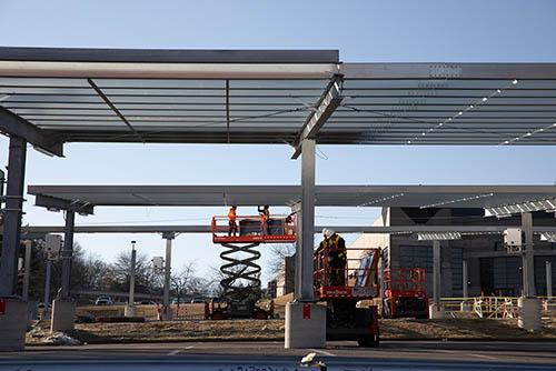 a construction crew working underneath the steel frame waiting to receive solar panels