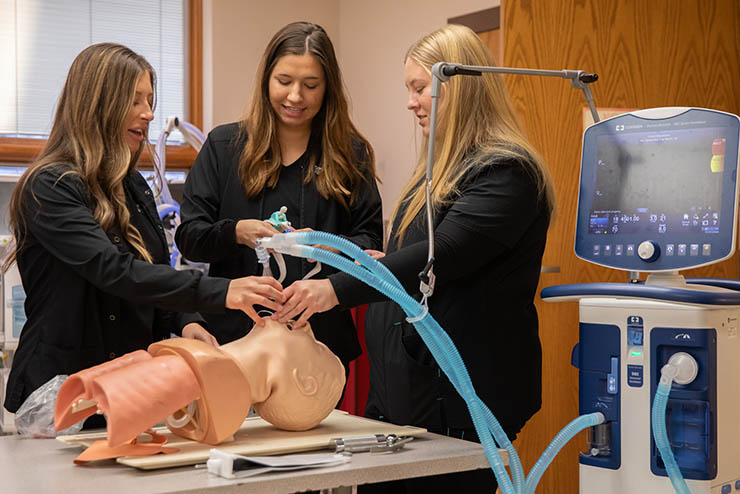 respiratory therapy students work with a training dummy during their class