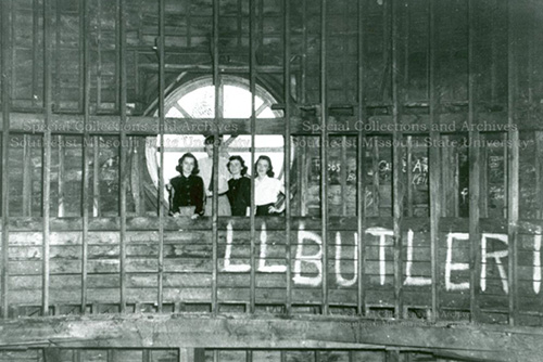 Students stand in the dome of Academic Hall, in front of a round window, behind guard rails.