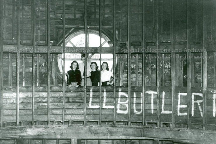 Students stand in the dome of Academic Hall, in front of a round window, behind guard rails.