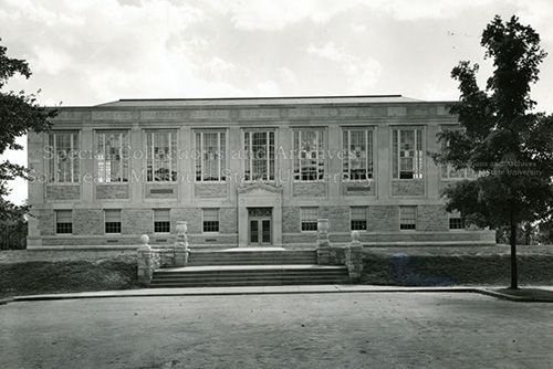 Photo of Kent Library when it was first built in the 1940s on a cloudy day, with trees on either side.