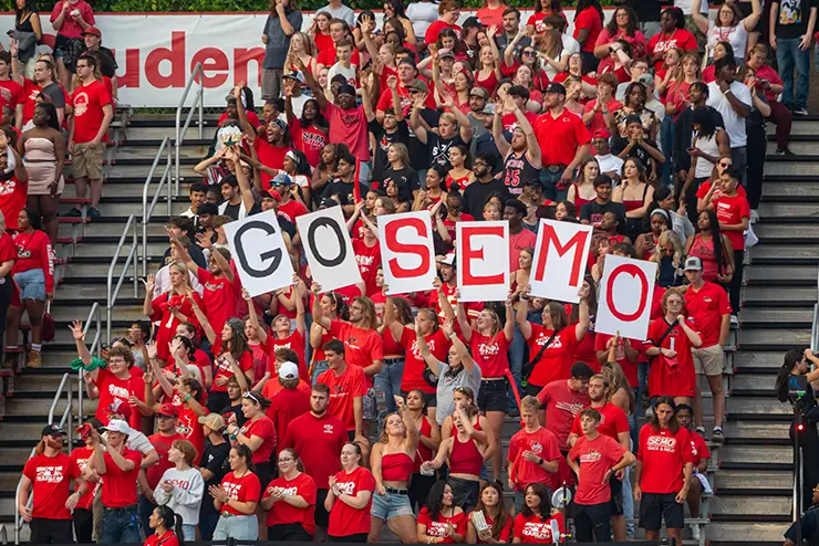 The Rowdy Crowd at a SEMO football game celebrate campus life, holding signs to spell out “go SEMO,” 