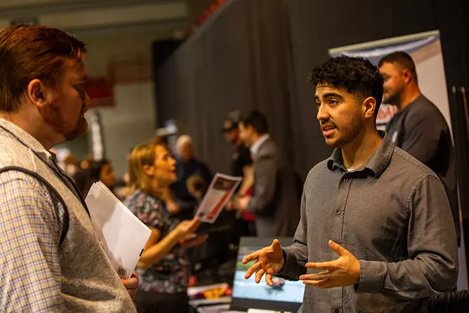 Two students in our communication sciences and disorders program converse at a career expo on campus. 