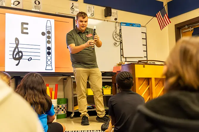 A music education student at SEMO, a top-rated music college, teaches elementary students proper recorder finger placement during a student teaching session.