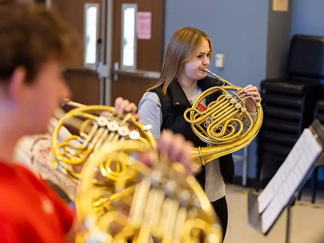 Jordan, a student in the music department at SEMO a top music school in Missouri, practices the French Horn in class with other students.