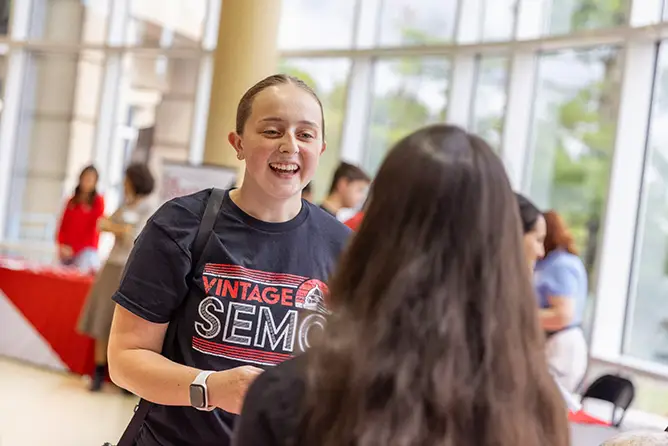 One student engaging with another student at an involvement fair on campus