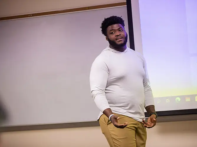 A student presents his final project in front of his accredited marketing program class. 
