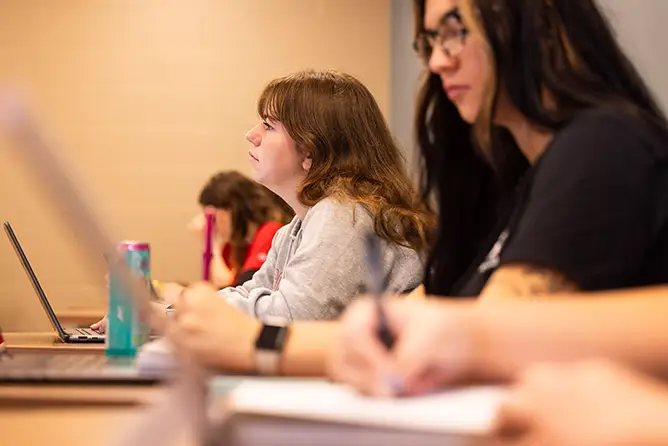 Students in a social work class with laptops out taking notes
