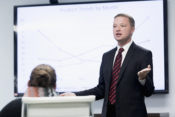 A SEMO student works on getting their MBA by giving a presentation with a graph on a whiteboard behind them. 