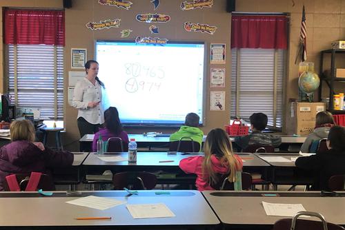 Using a smartboard while student teaching, Summer teaches math to an elementary school class.