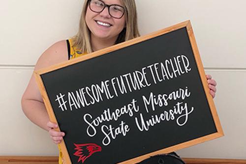 Megan smiles and holds a sign reading “#AWESOMEFUTURETEACHER SOUTHEAST MISSOURI STATE UNIVERSITY”.