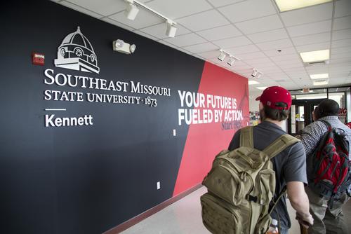 Students look at an interior wall featuring branded graphics at the Kennett Campus.