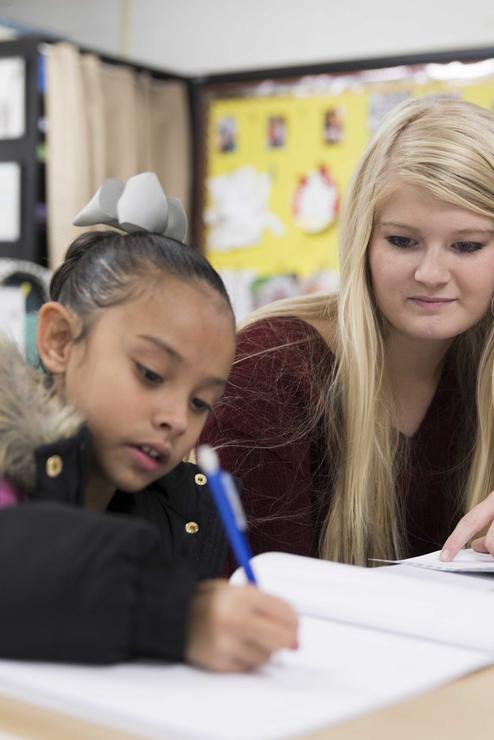 A student helps a young girl with her homework at the Read to Succeed Reading Academy in Sikeston.