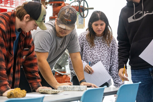 Four students surround a table which holds soil samples.