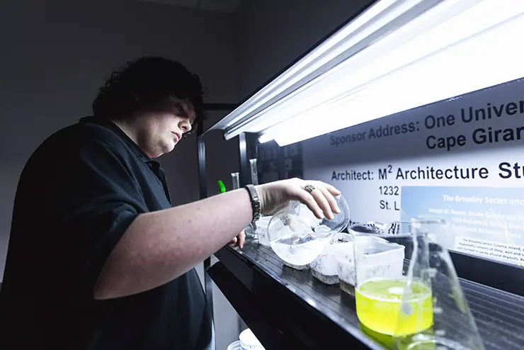 a Kennett regional campus student studying agirculture works under a lab hood with chemicals
