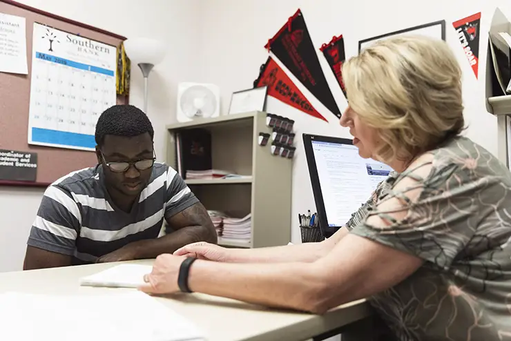 a student sits with an advisor going over documents