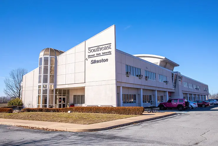 A view of the outside of the Sikeston Regional Campus with cars around it.
