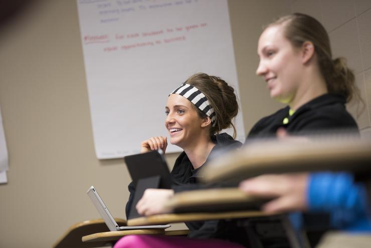 An education student smiles next to a peer in class.