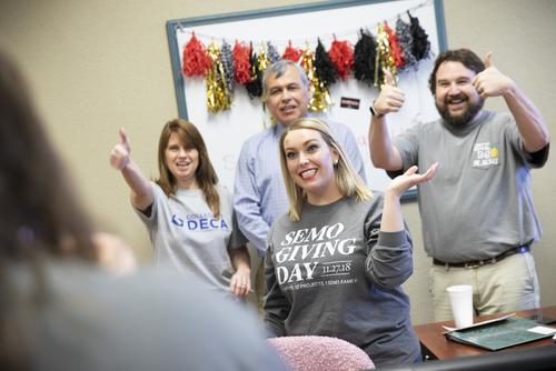 People smile, one in a SEMO Giving Day t-shirt, while helping with the fundraising event.