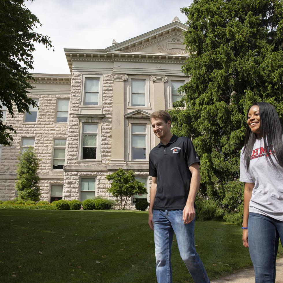 Students in SEMO apparel smile while walking past Academic Hall.  