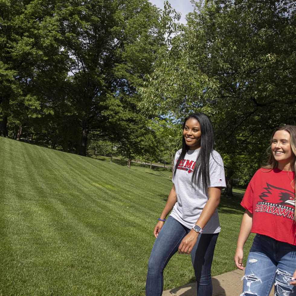 Students in SEMO attire smile while walking across campus. 