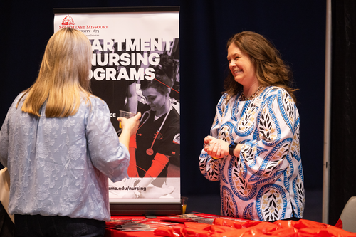 Two people speaking at Power of Women conference and smiling