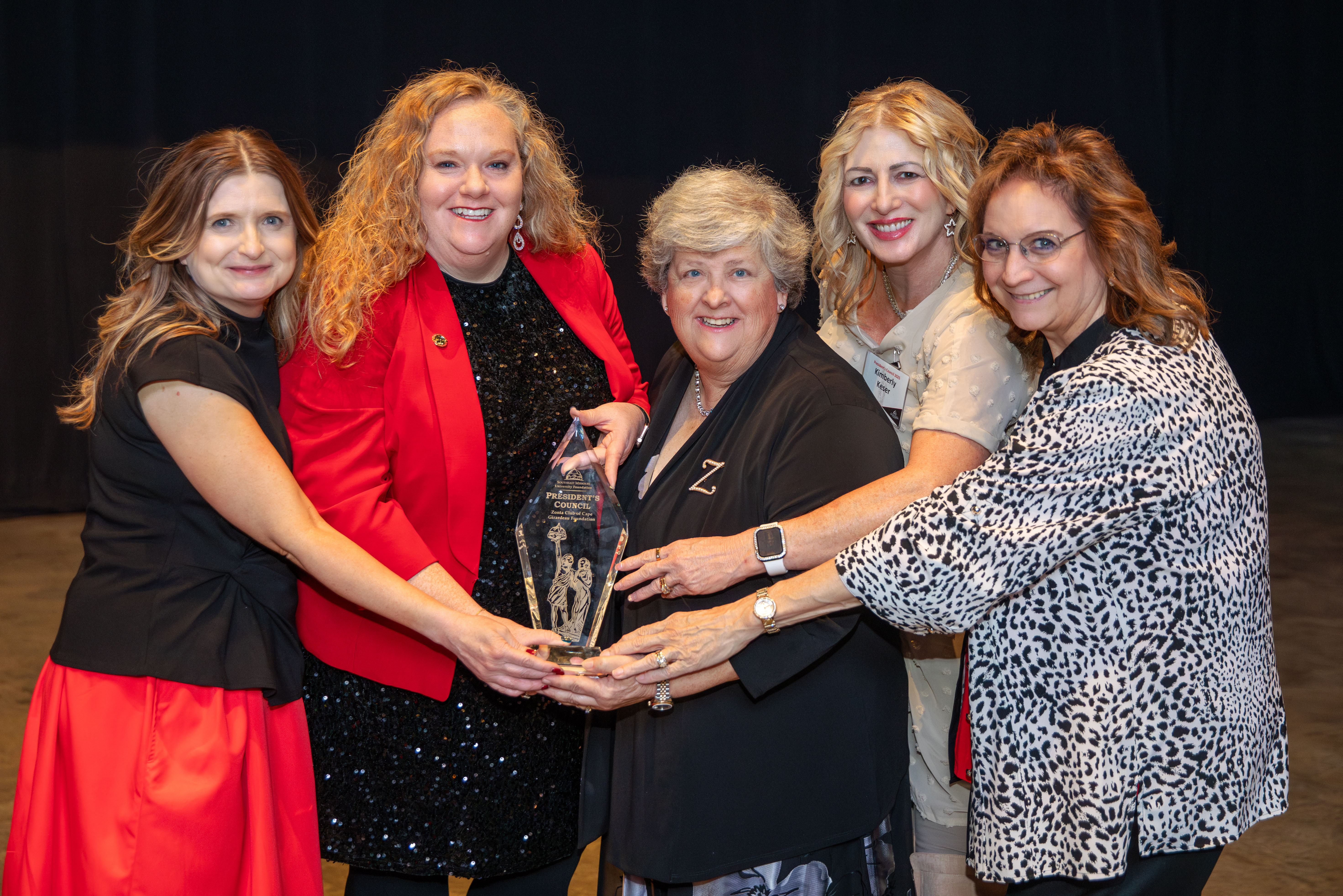A group of women hold a 'President's Council' award.