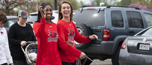 Students smile, one waves, while wearing Redhawks shirts and taking part in a Walk for Women event.