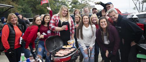 A group smiles for the camera while tailgating during homecoming.
