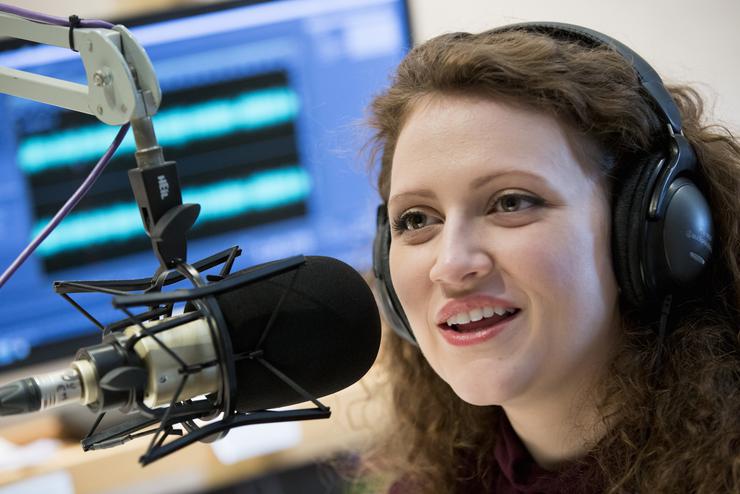 A student speaks into a KRCU microphone in a studio. 