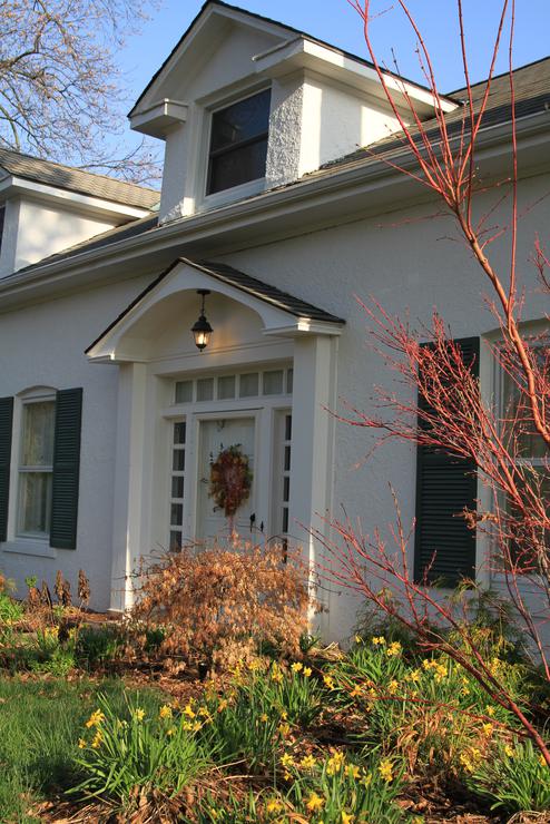 A bright red wreath hangs on the door of Wildwood, framed by fall trees.