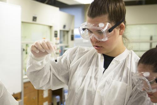 A student studies a test tube while doing a chemistry experiment.