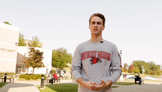 Elliot Siekmann stands in the courtyard in front of Johnson Hall on a sunny autumn day.