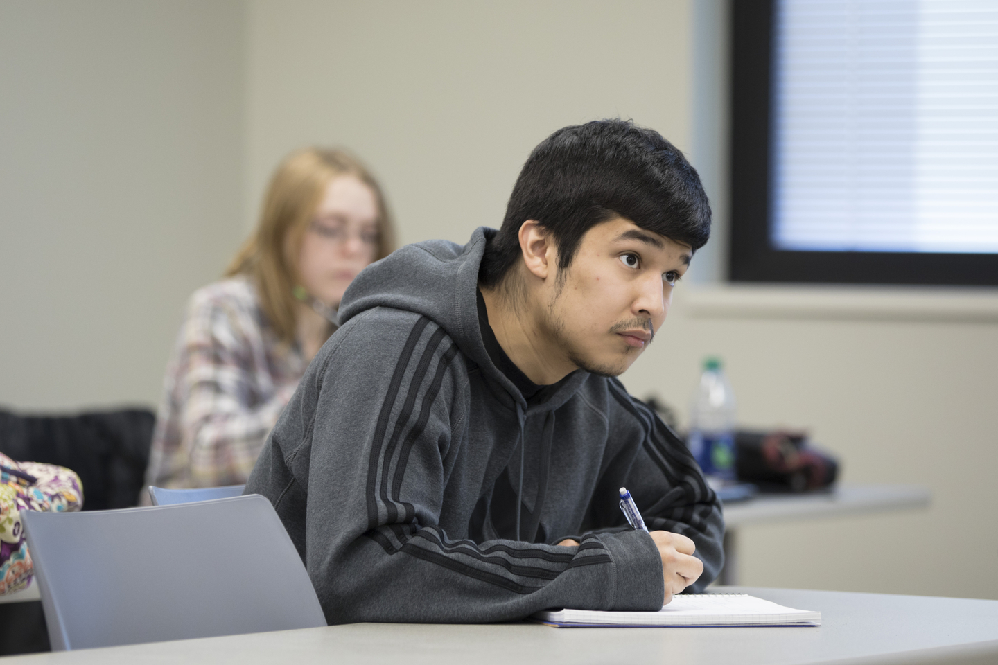 A student writes in a notebook during a lecture.