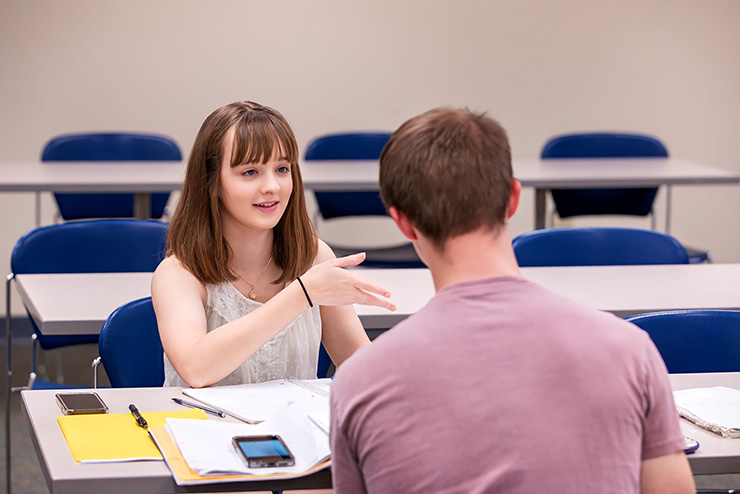 Two students are doing work together at a desk during an Accounting class.