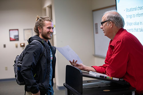 A student listens next to socially-distanced peers in a classroom. 