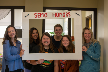 A group of students smiling and holding up a frame that says "SEMO Honors". 