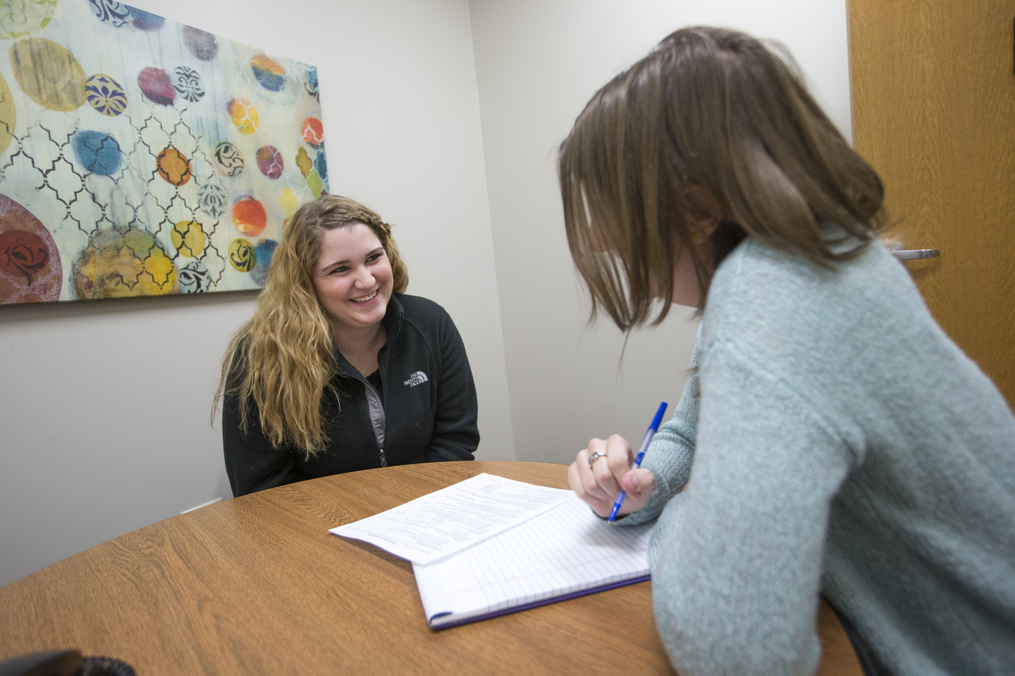 A student smiles as she has their resume reviewed by career services staff.
