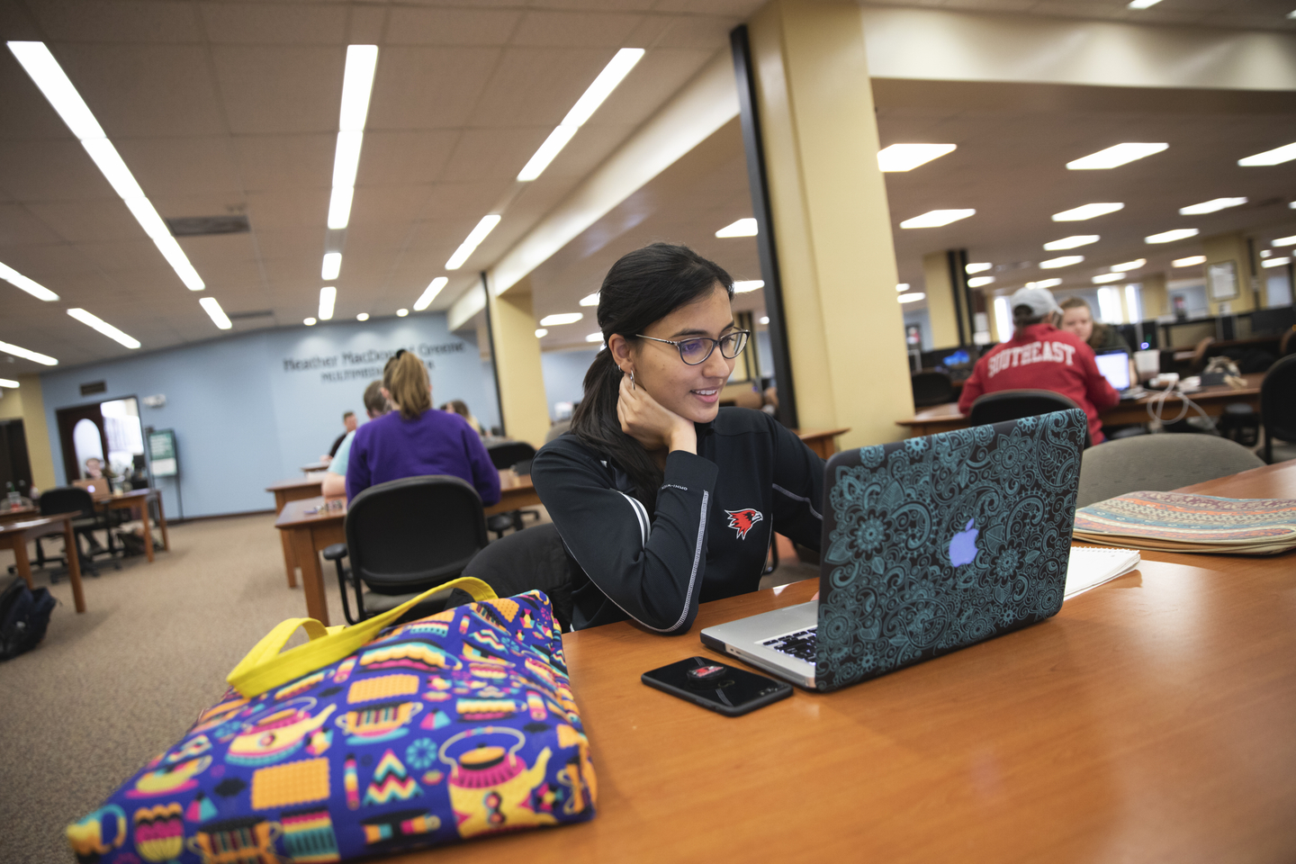 A student studies on a laptop at a table inside Kent Library.