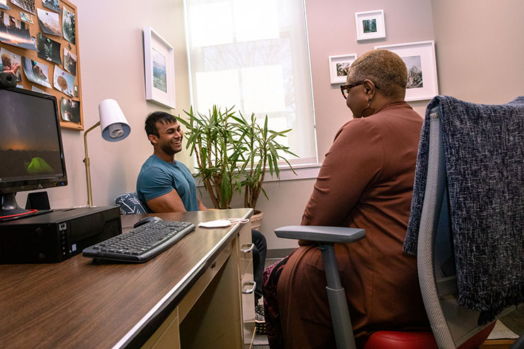 A student wearing scrubs inspects a sample cup.