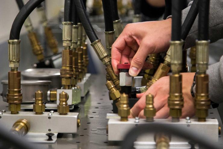Hands work with machinery inside a hydraulics lab. 